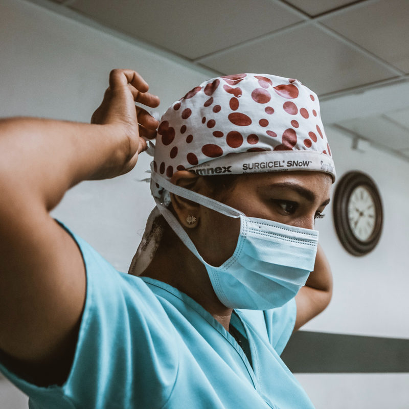 Health care worker tying mask and surgical cap